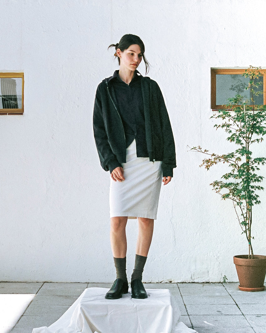 Lifestyle photo of a person wearing Pedal Loafer Pull-up Leather Black shoes with a dark green sweater and light grey skirt