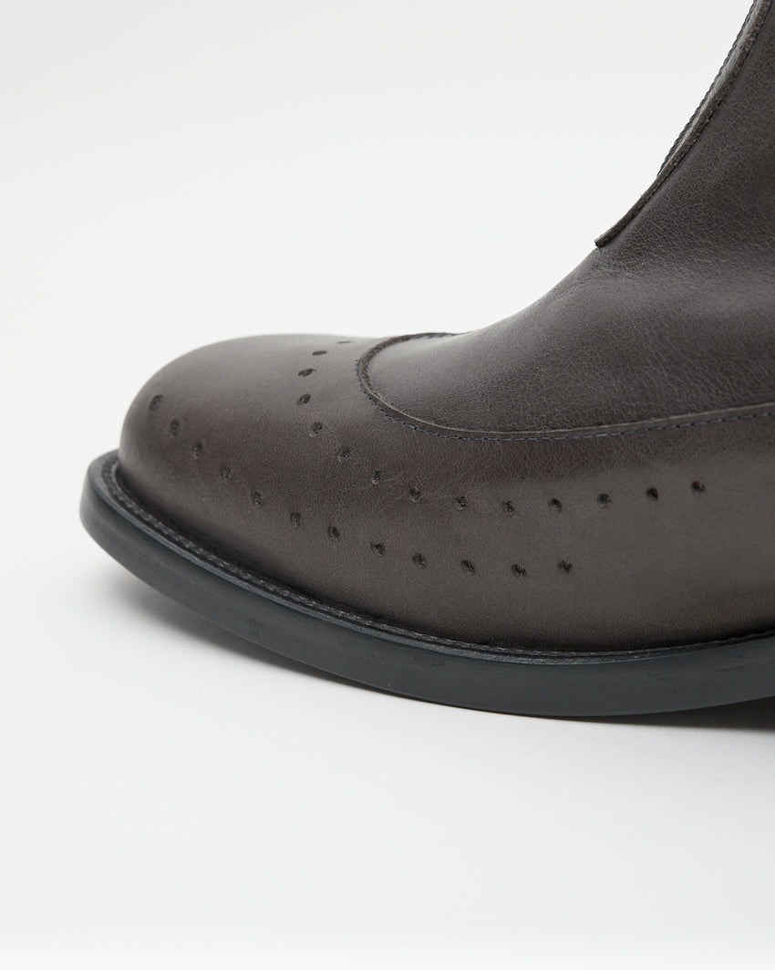 Close-up side profile of the Cove Boot Jeongli Grey toe showing brogue perforation dots and the block heel base