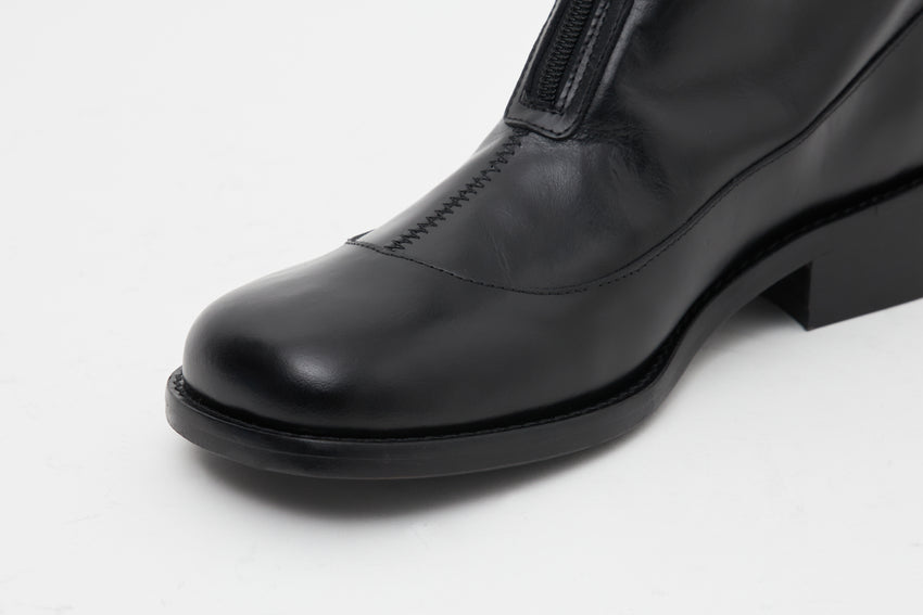Close-up side view of the Cove Boot's toe and front zip in pull-up leather black