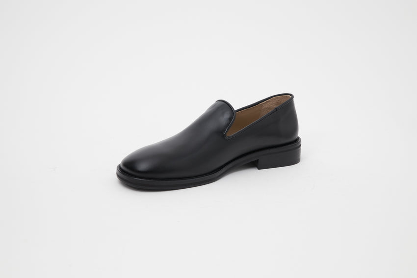 Angled side view of single Legacy Slipper shoe in black calfskin leather.
