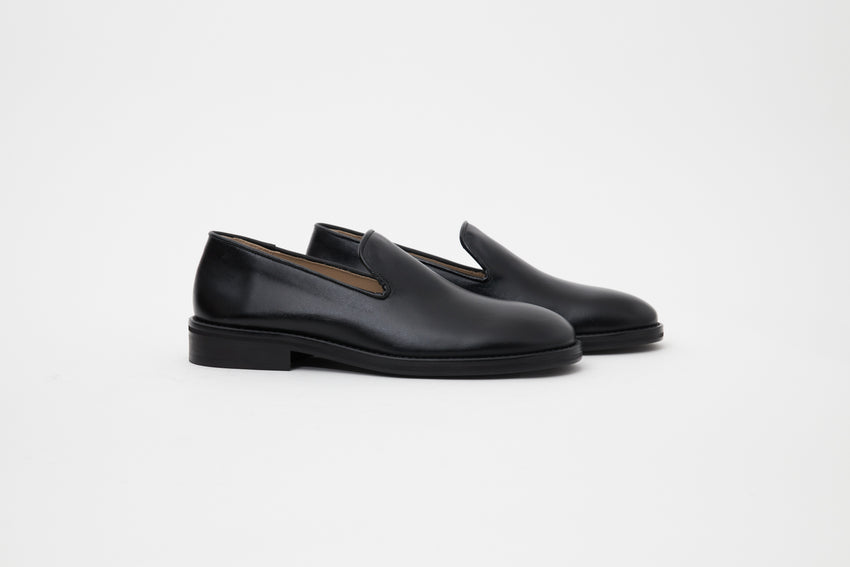Staggered side profile of Legacy Slipper pair in black calfskin leather.