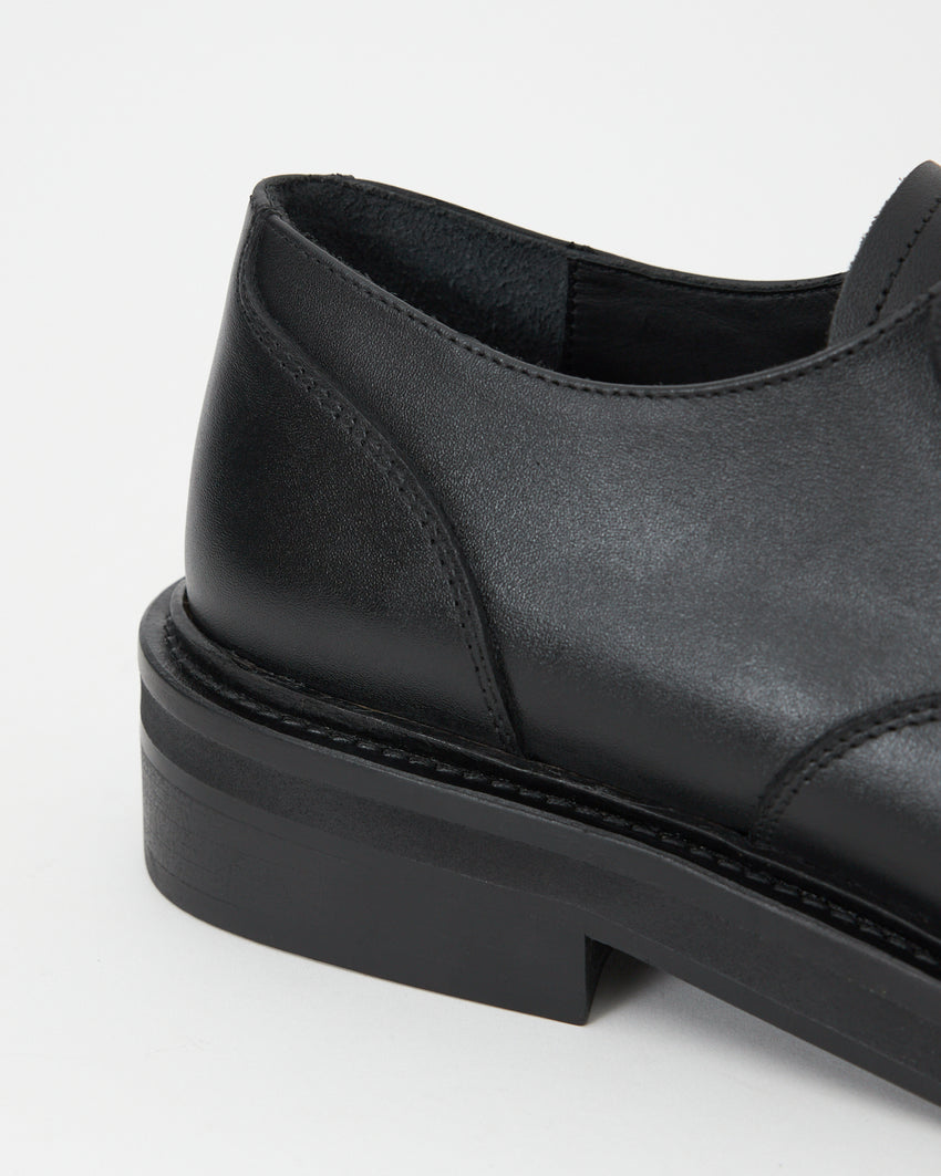 Close-up angled view of the Mid-Heel Derby shoe's toe and block heel in calfskin black