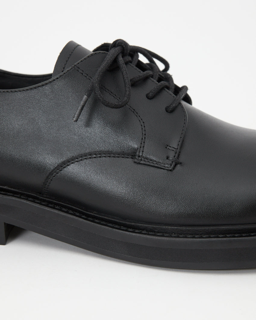 Side profile of the Mid-Heel Derby shoe in calfskin black, showing the full silhouette and block heel