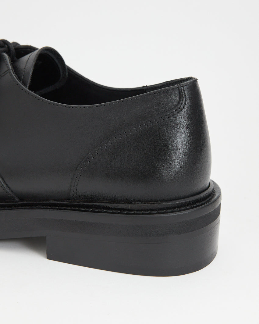 Close-up back view of the Mid-Heel Derby shoe in calfskin black, showing the heel counter