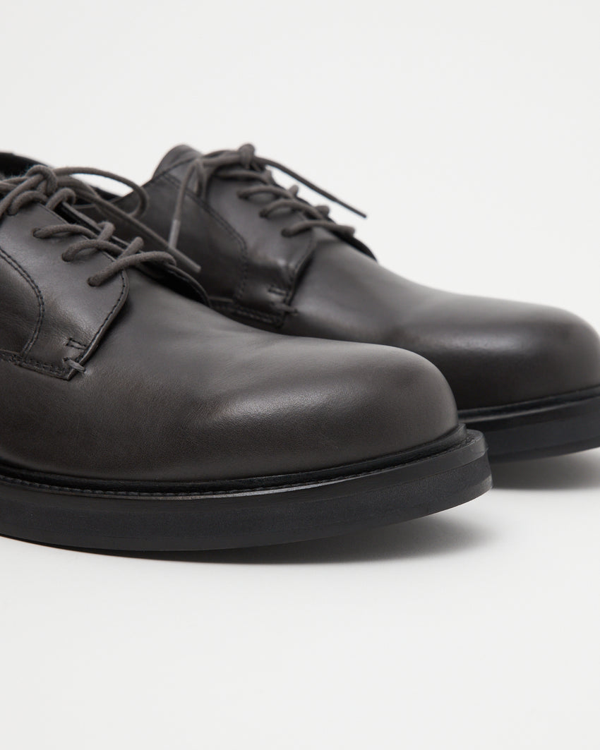 Close up three quarter view of Mid-Heel Derby pair in dark grey oil nappa leather toe box.