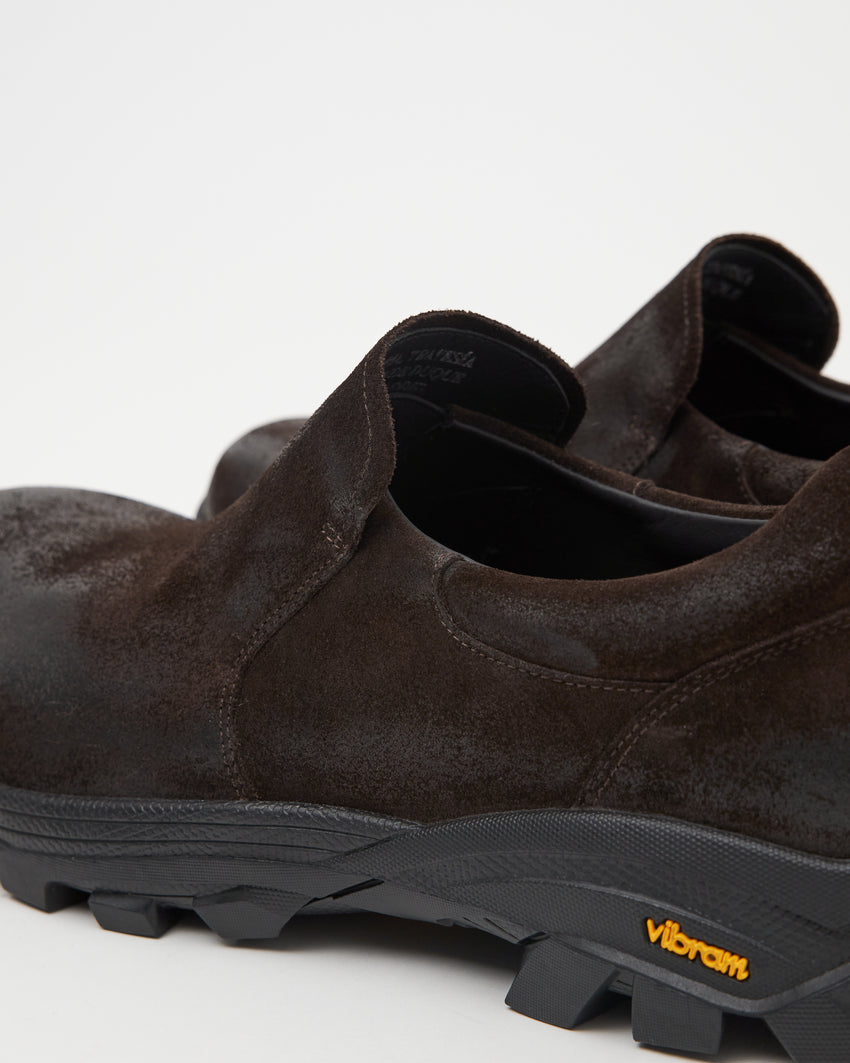 Close-up angled back view of a single Non-Safety Slip-on Waxed Suede Deep Brown shoe showing black interior collar, heel, and Vibram sole tag