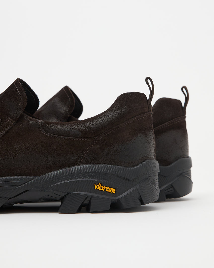 Close-up angled back view of a pair of Non-Safety Slip-on Waxed Suede Deep Brown shoes showing heels and Vibram sole tag
