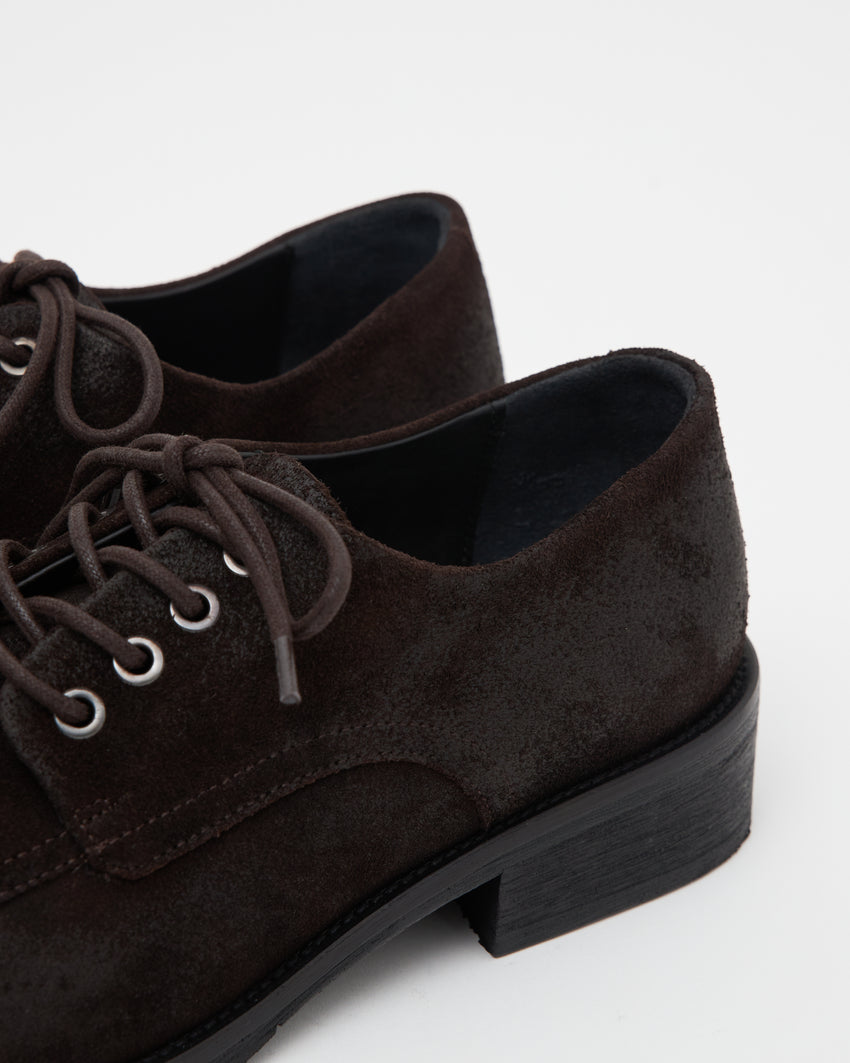 Close-up angled front view of a pair of Old Buster Waxed Suede Deep Brown shoes showing laces and tan interior lining